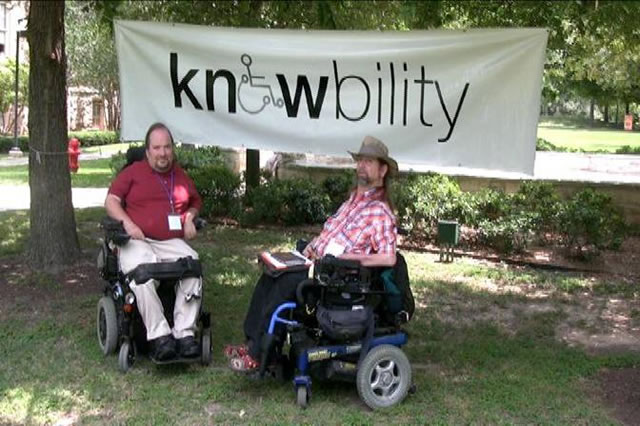Dave and Gene pose in front of a Knowbility banner